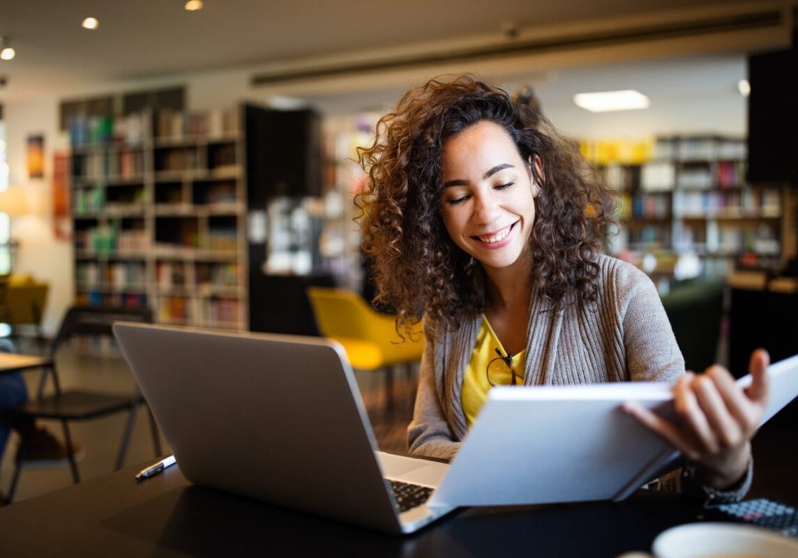 GettyImages-1266628951 A woman sitting at a table with two laptops.