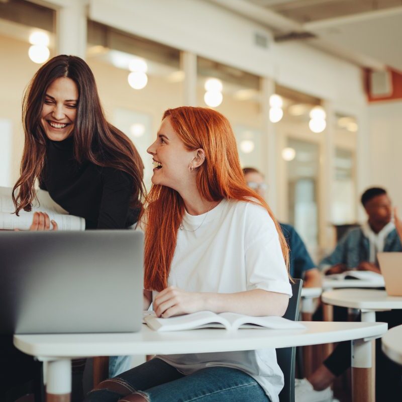 GettyImages-1348870264 Two women sitting at a table with laptops.