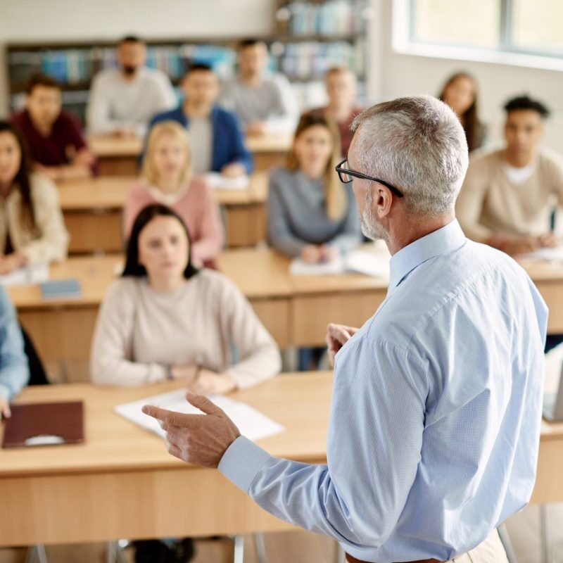 GettyImages-1366724877 A man in glasses is giving a lecture to students.